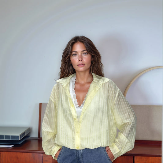 Detalhe aproximado do decote da Blusa Olívia mostrando o top básico branco com acabamento em renda delicada por baixo da transparência sutil do tecido.