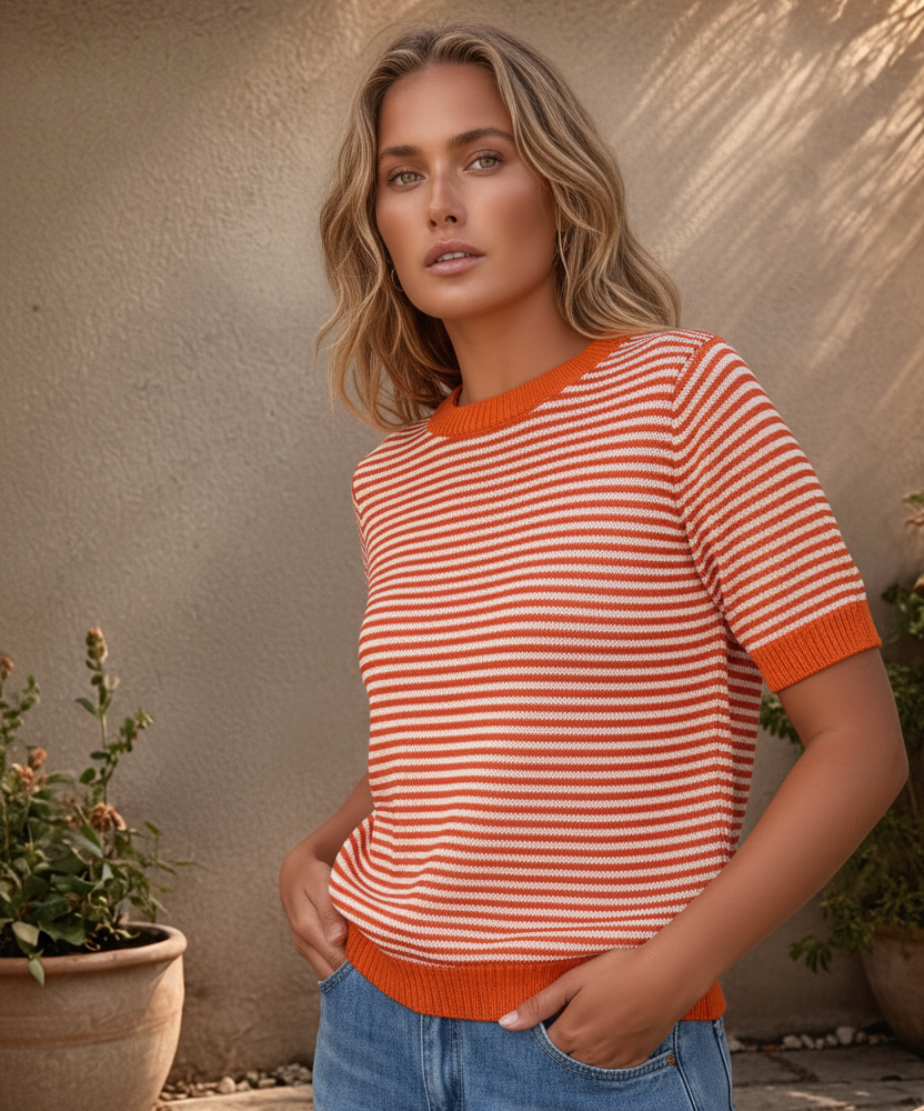 Grande plano de camisola de malha às riscas com destaque para os remates em vermelho vivo na gola e nas mangas em modelo posando de lado