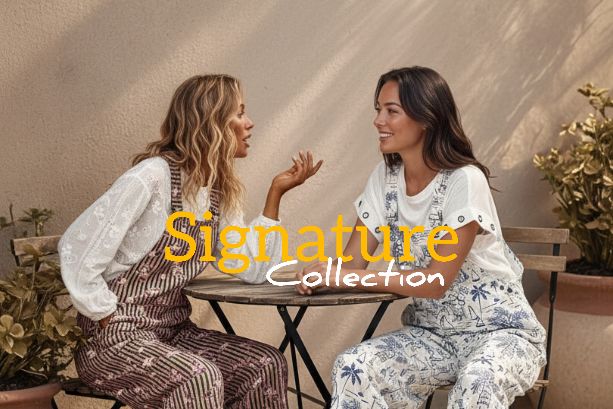 Duas modelos com jardineiras da coleção Signature da marca Josephine, sentadas à mesa a conversar