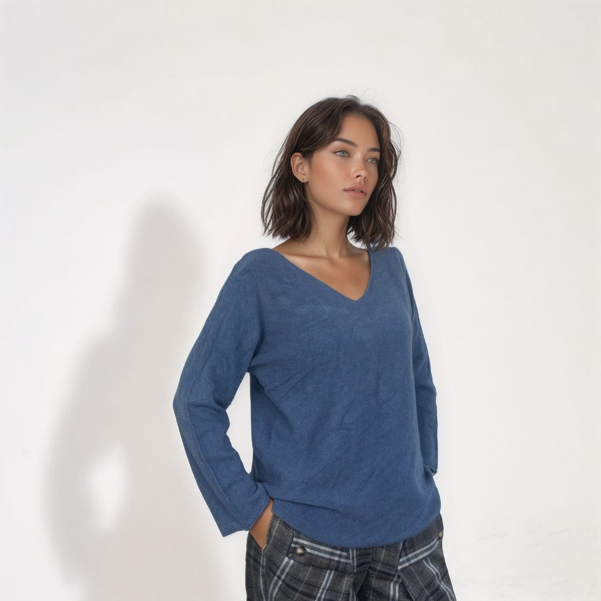 Camisola Kika de malha azul ganga, com decote em V e mangas compridas, combinada com calças de xadrez cinzento. Moda feminina Josephine.