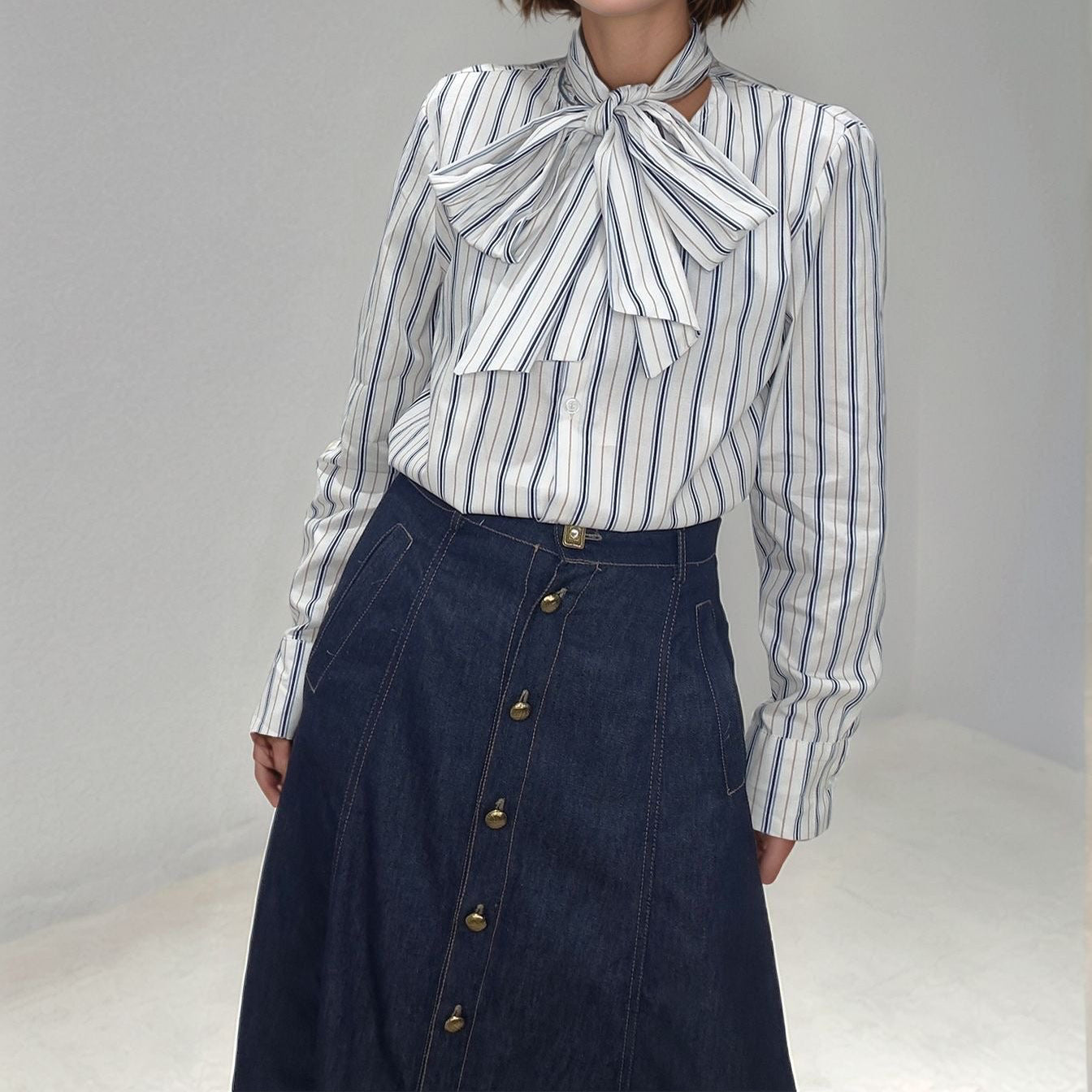 O cós da saia denim, em destaque o botão metálico exclusivo e o acabamento premium da costura.