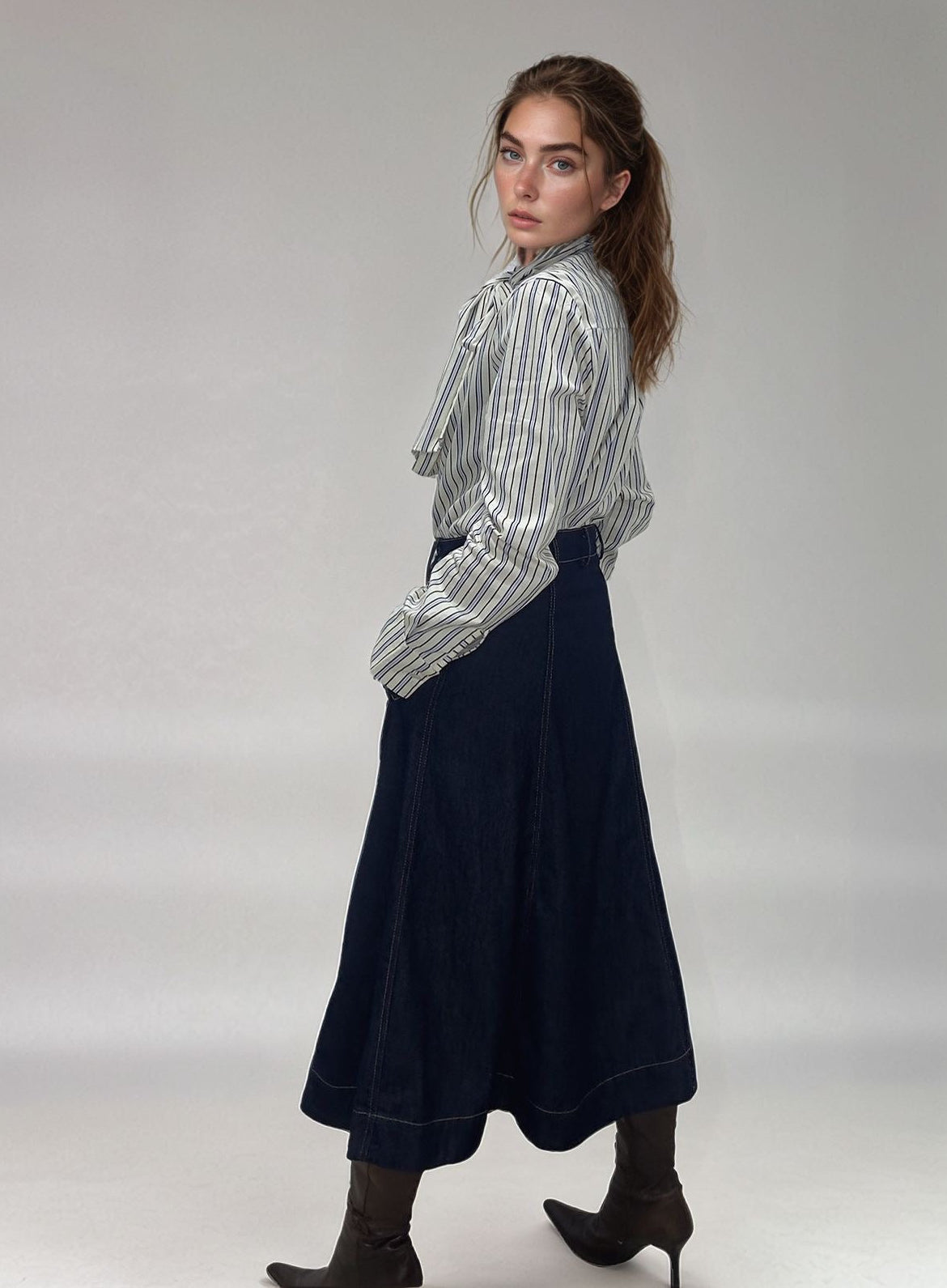 Modelo posando com as mãos nos bolsos da saia denim, evidenciando o corte evasê e a sofisticação do conjunto com a Blusa Sophia.