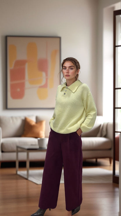 Woman in a light yellow polo sweater and wide-leg purple pants from Josephine in a modern living room