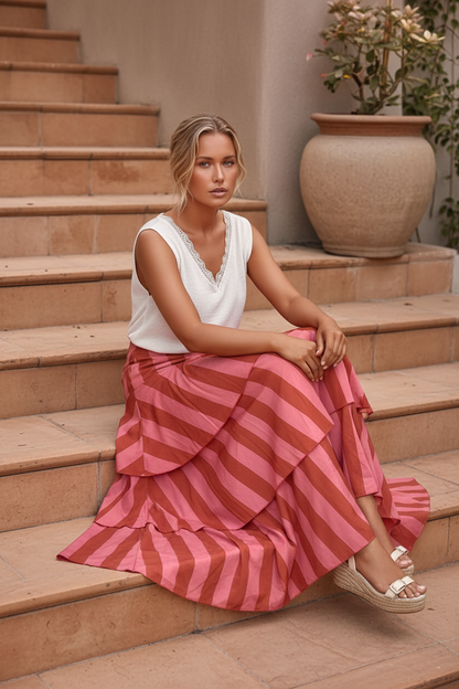  Modelo sentada nas escadas vestindo saia de folhos rosa e terracota destacando o movimento do tecido de algodão e o cós elástico que veste até tamanho