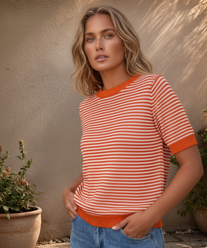 Grande plano de camisola de malha às riscas com destaque para os remates em vermelho vivo na gola e nas mangas em modelo posando de lado